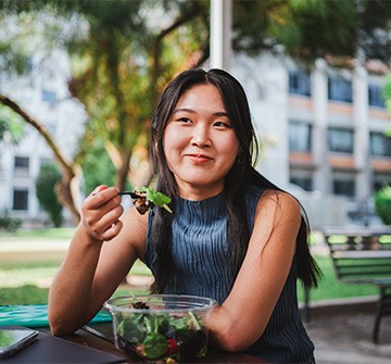 Teen girl smiling while eating lunch outside