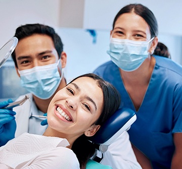 a dental patient smiling and chatting with two dentists