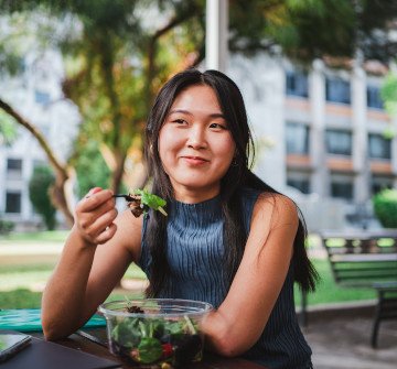 Teenage girl smiling while eating healthy meal outside