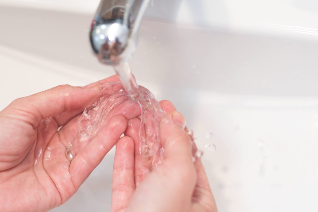 Patient rinsing clear aligners in sink