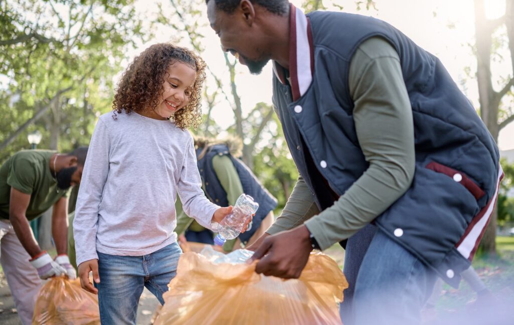 Smiling child and parent participating in trash pick up