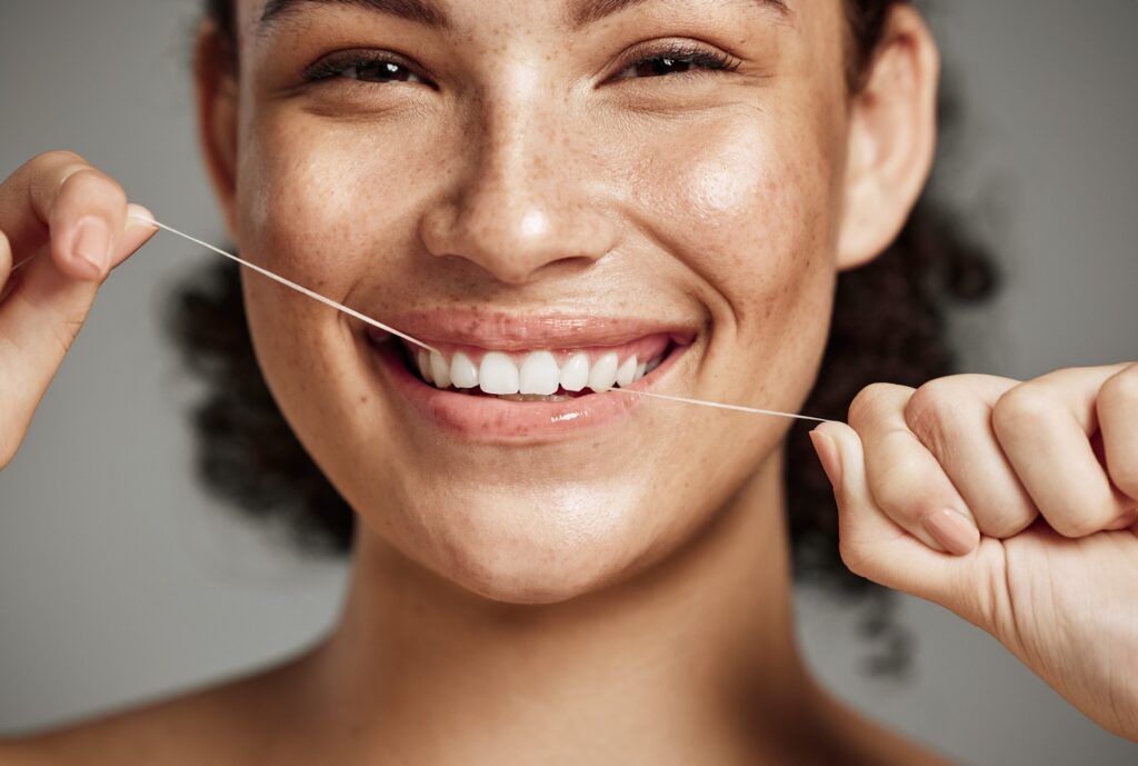 Closeup of woman smiling while flossing her teeth