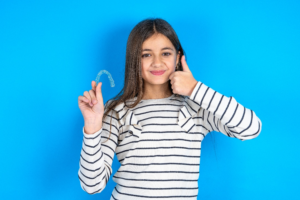 a young patient holding her Invisalign aligner